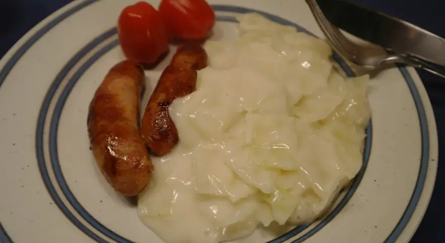 Tallrik med stuvad vitkål, två korvar och körsbärstomater. En klassisk svensk husmanskosträtt.
