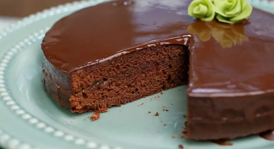 En saftig chokladkaka med blank glasyr, perfekt för ett sachertårta recept. Garnerad med gröna marsipanrosor.