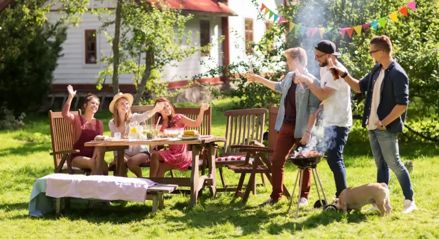 Vänner njuter av grillfest och lekar till 5 kamp i trädgården. En liten gris nosar i gräset.
