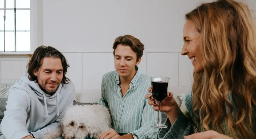 Familj spelar julklappsspelet. Alla får en julklapp, men reglerna kan vara knepiga! En vit hund vilar på soffan.