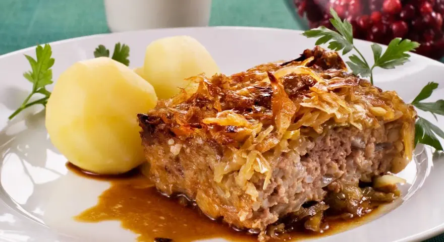 En bit kålpudding med kokt potatis och en skvätt sås. Perfekt för ett klassiskt kålpudding recept.