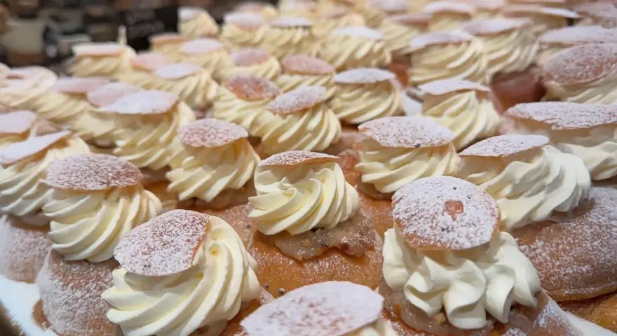 En hel hylla full med semlor, redo för semmeldagen. Krämig grädde och pudrat florsocker.