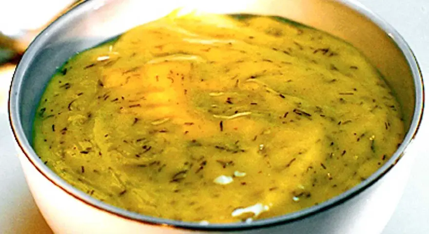 En skål med krämig gravlaxsås, perfekt för ditt gravlaxsås recept. Dill och senap syns i den gula såsen.
