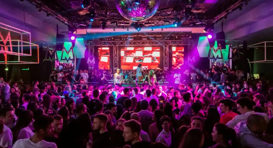 Folk dansar och festar på en 30-årsfest. En discokula hänger i taket och scenen lyses upp av färgglada lampor.