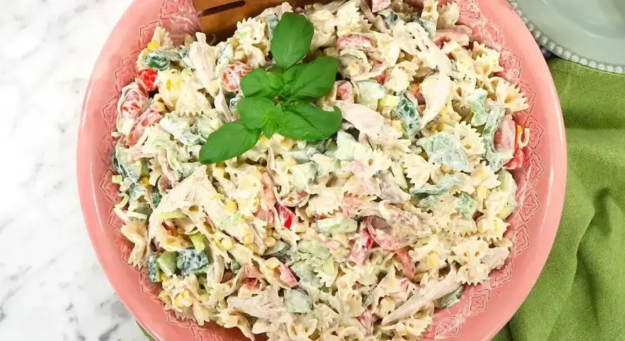 En krämig pastasallad med kyckling, grönsaker och en härlig basilika. Perfekt för ett snabbt pastasallad recept.