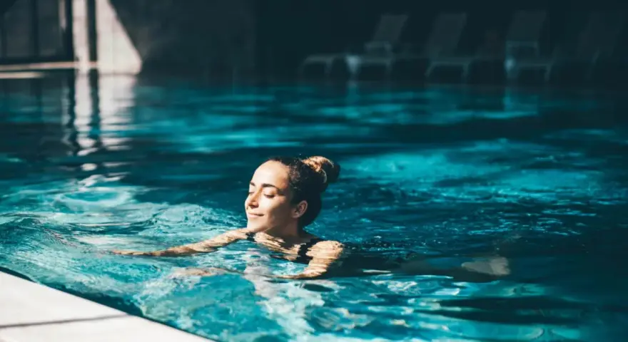 Avslappnad kvinna njuter av ett lugnt bad i en inomhuspool, en perfekt bild av spa i Sverige.