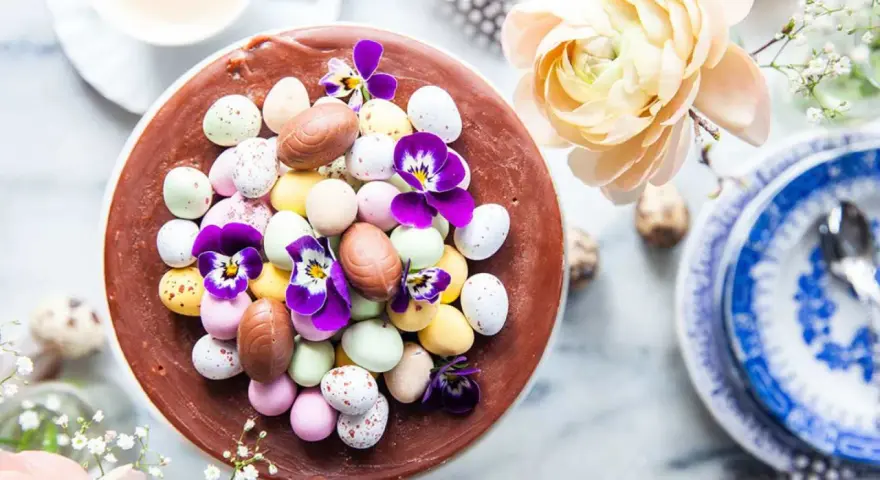 En chokladtårta dekorerad med påskägg i olika färger och violer. En perfekt påsktårta choklad för firandet.