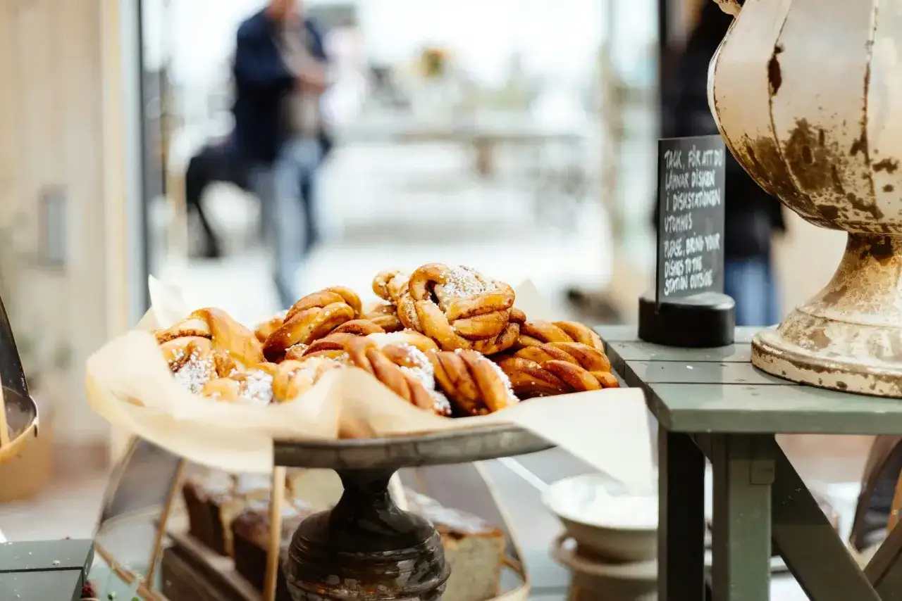 En h&ouml;g med kanelbullar p&aring; ett fat, perfekt f&ouml;r ett annorlunda caf&eacute;. I bakgrunden syns en person och en skylt p&aring; engelska.
