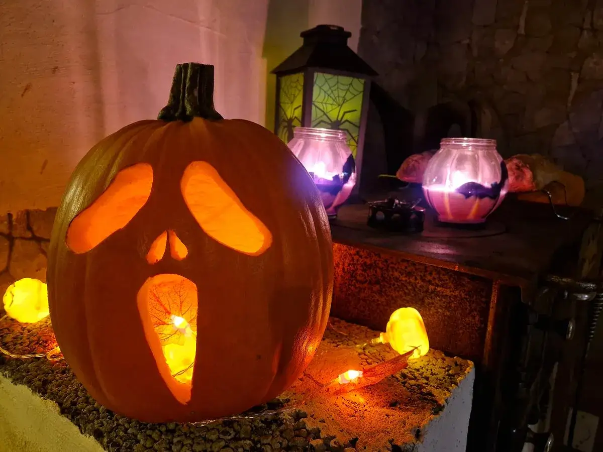En utskuren pumpa med skr&auml;mt ansikte lyser upp inf&ouml;r halloween helg. Sm&aring; ljus och lyktor skapar en kuslig st&auml;mning.