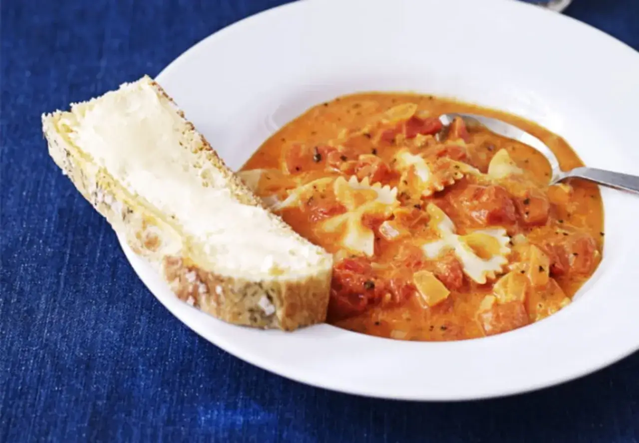 En krämig tomatsoppa med fjärilspasta och en skiva smörgås. Ett perfekt tomatsoppa recept för en mysig kväll.