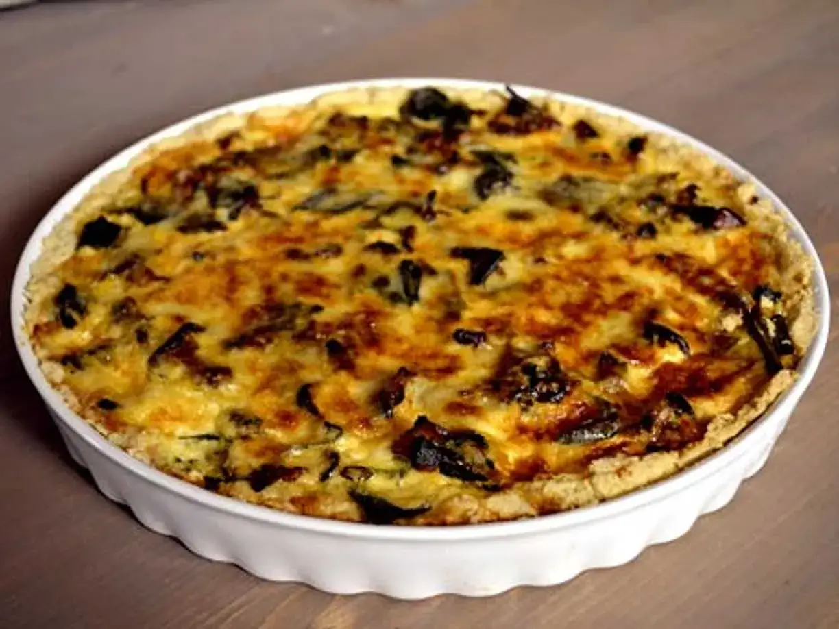 En gyllene kantarellpaj i en vit pajform, perfekt för ett höstligt kantarellpaj recept.