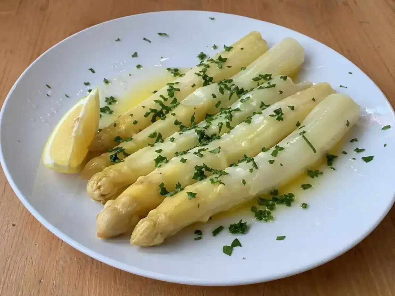 En tallrik med vit sparris, sm&auml;lt sm&ouml;r, persilja och en citronklyfta. En klassisk och uts&ouml;kt r&auml;tt.