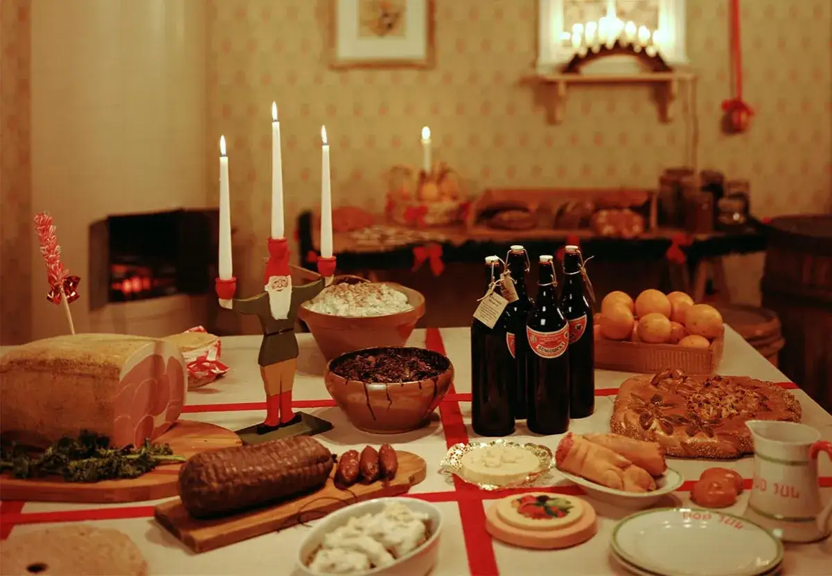 Julbordet är dukat med julskinka, korvar, sill, risgrynsgröt, apelsiner och julmust. En tomte med ljus står i centrum. En perfekt checklista julbord!