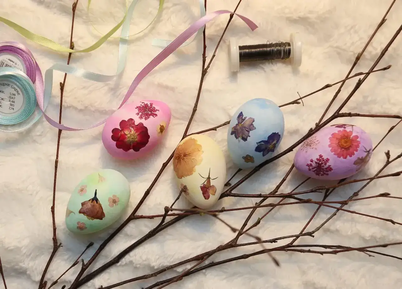 Vackra p&aring;sk&auml;gg dekorerade med torkade blommor, redo att h&auml;ngas upp som en del av en p&aring;sk kalender. Band och tr&aring;d ligger bredvid.