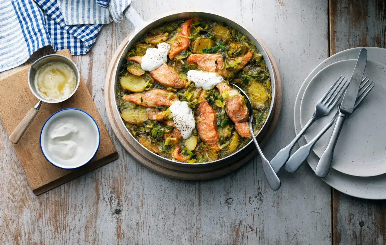 En härlig panna med lax, potatis och purjolök, toppad med en klick gräddfil. Ett perfekt lax recept för en mysig middag.