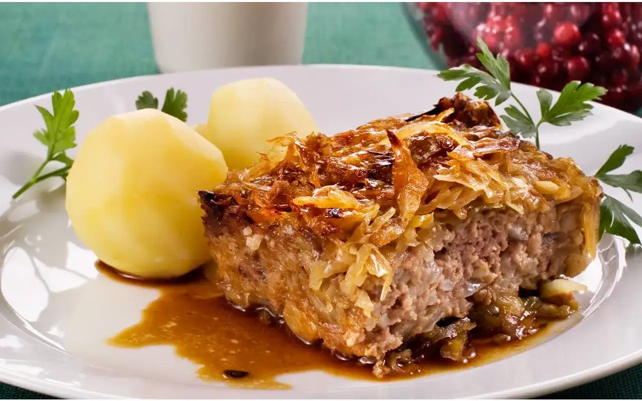 En bit k&aring;lpudding med k&ouml;ttf&auml;rs och k&aring;l, serverad med kokt potatis och en skv&auml;tt s&aring;s. Ett klassiskt svenskt recept!