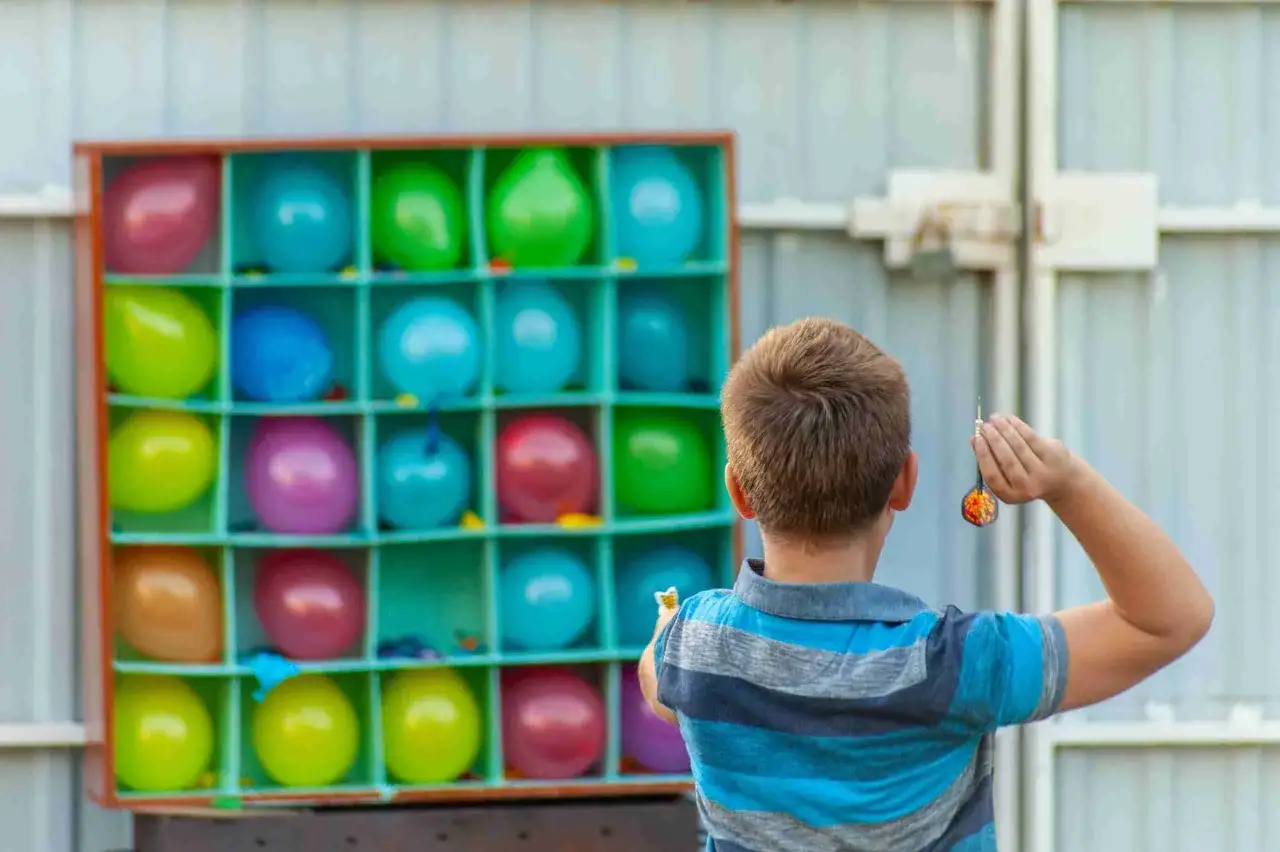 Pojke siktar med pil p&aring; ballonger i ett spel. Perfekt f&ouml;r fysiska lekar f&ouml;r barn p&aring; kalas eller tivoli.