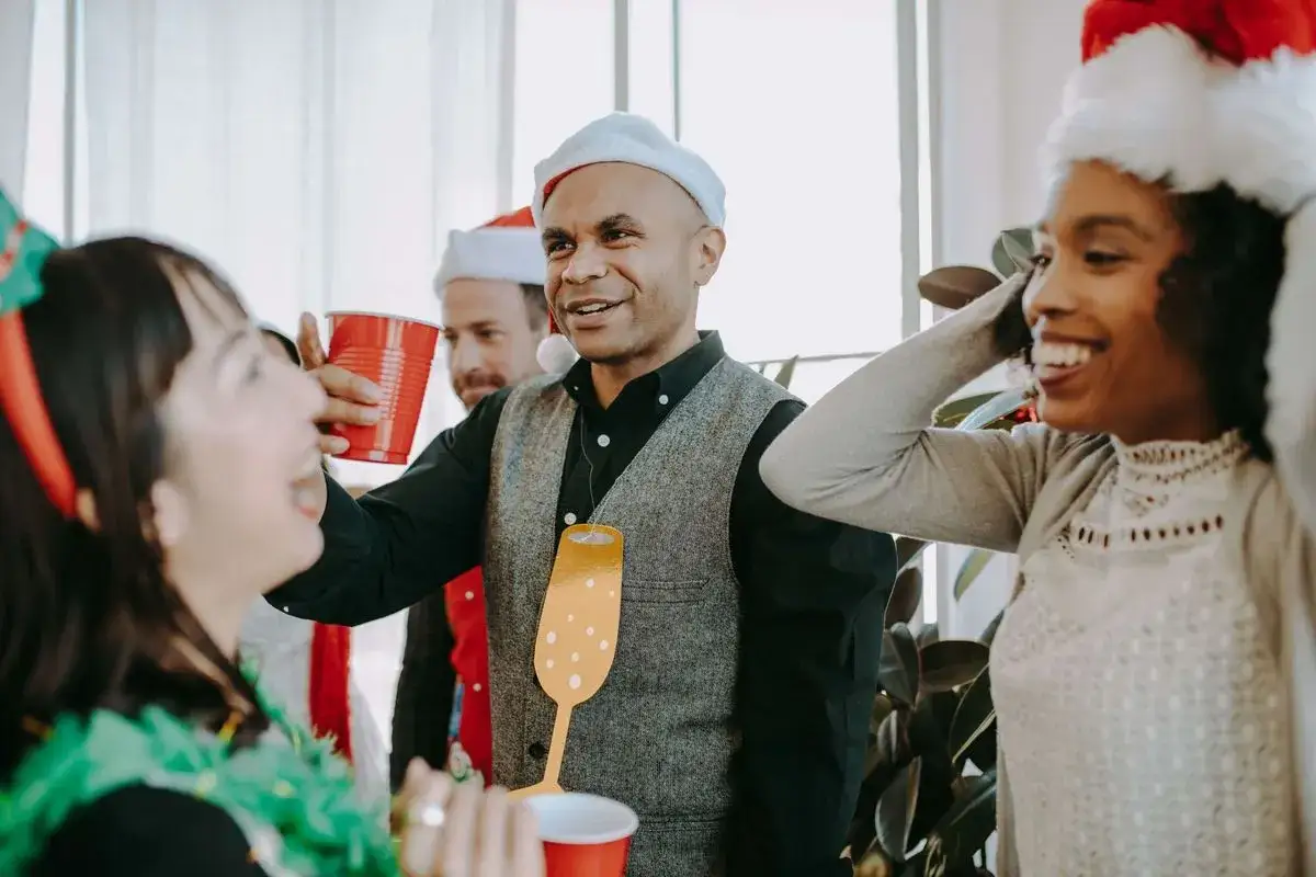 Glada kollegor med tomteluvor och r&ouml;da muggar firar lekar p&aring; julfest jobbet.