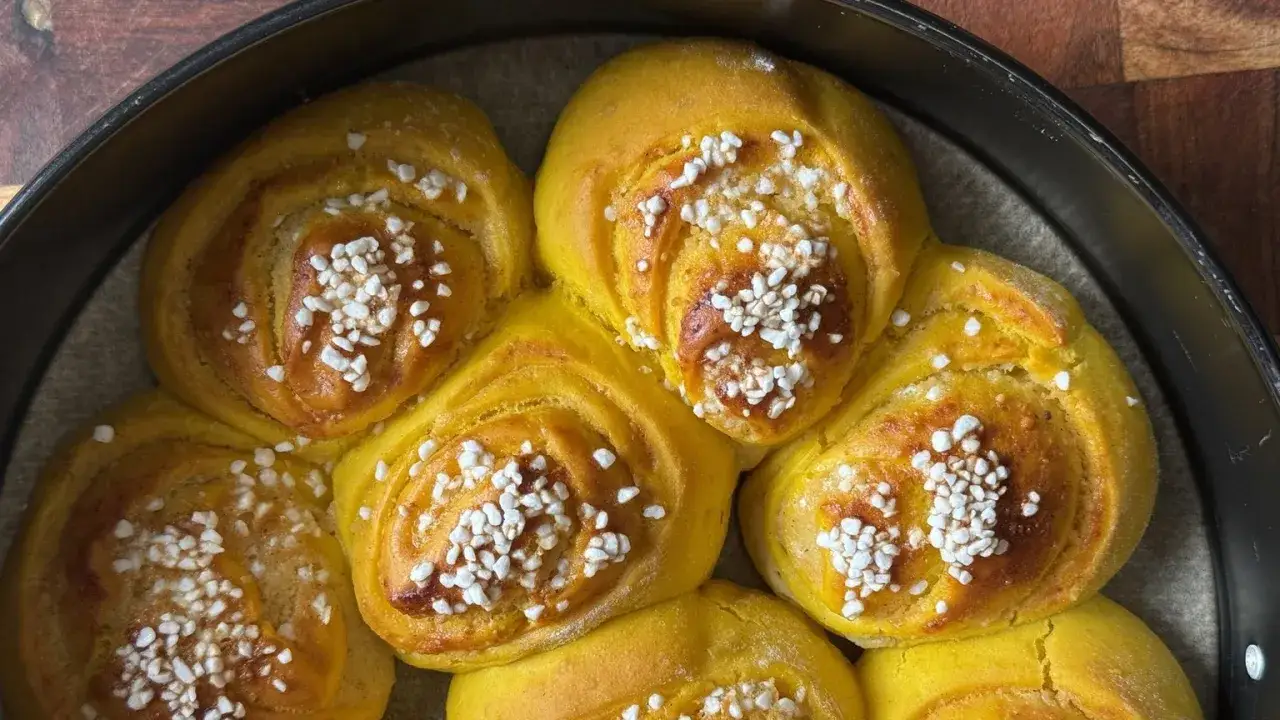 Nybakade lussebullar med kesella, gyllene och toppade med pärlsocker, redo att avnjutas.