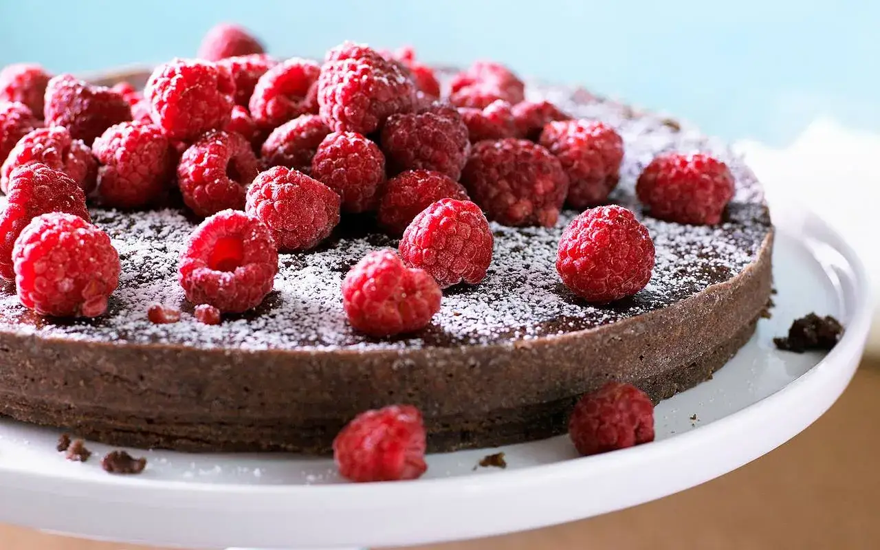 En saftig kladdkaka med fudge, toppad med färska hallon och pudrad florsocker. En dröm för alla chokladälskare!