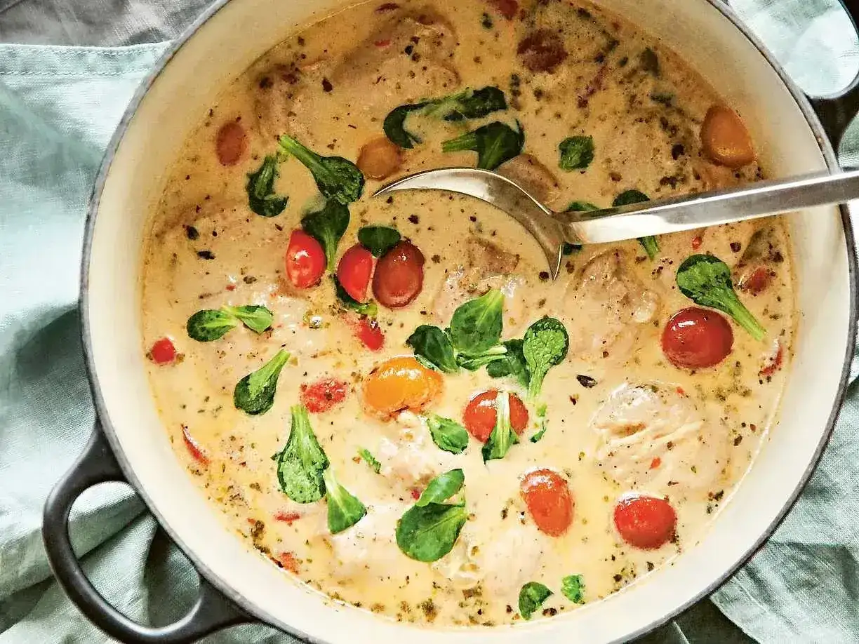 Krämig kycklinggryta med körsbärstomater och gröna blad. Ett enkelt kyckling recept som ser utsökt ut.