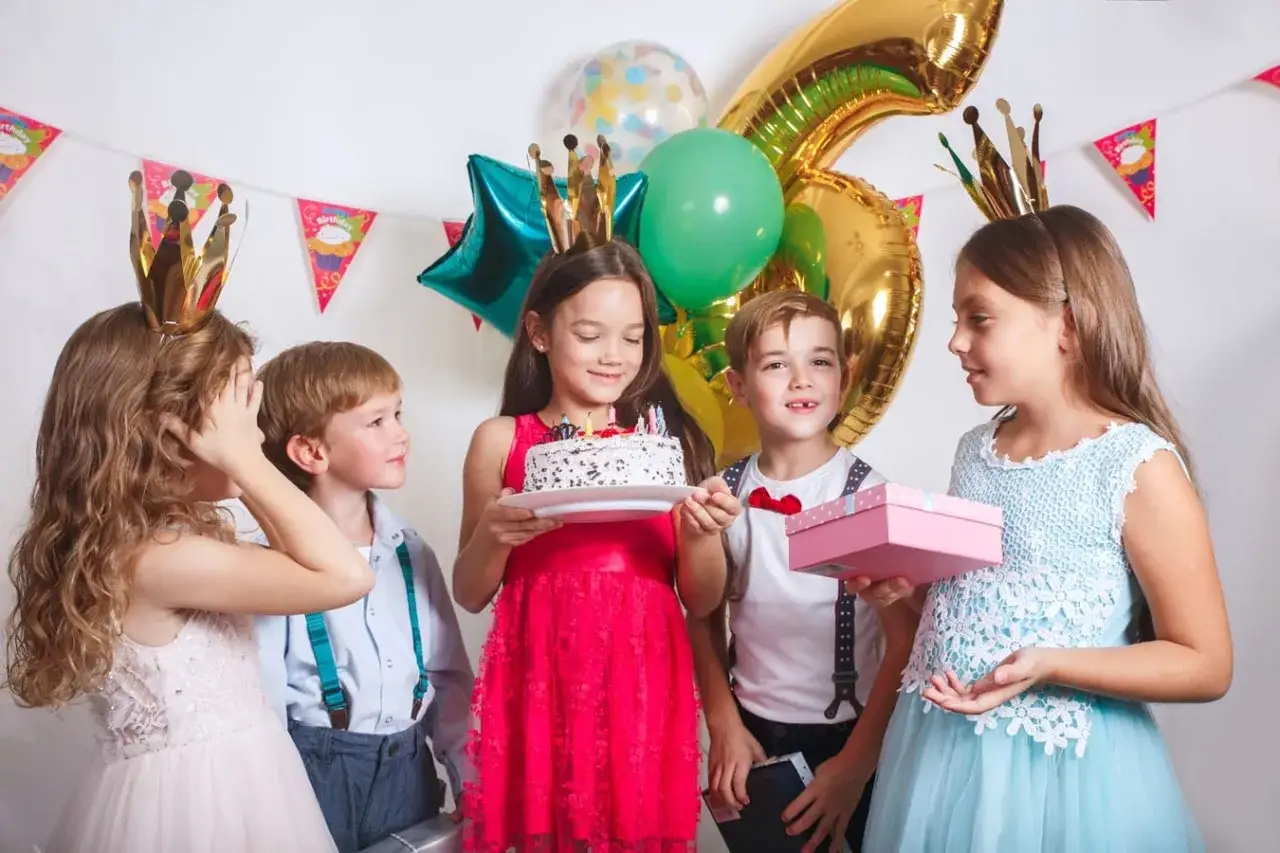 Barn med kronor firar f&ouml;delsedag med t&aring;rta och presenter. S&aring; h&auml;r leker 6-&aring;ringar!