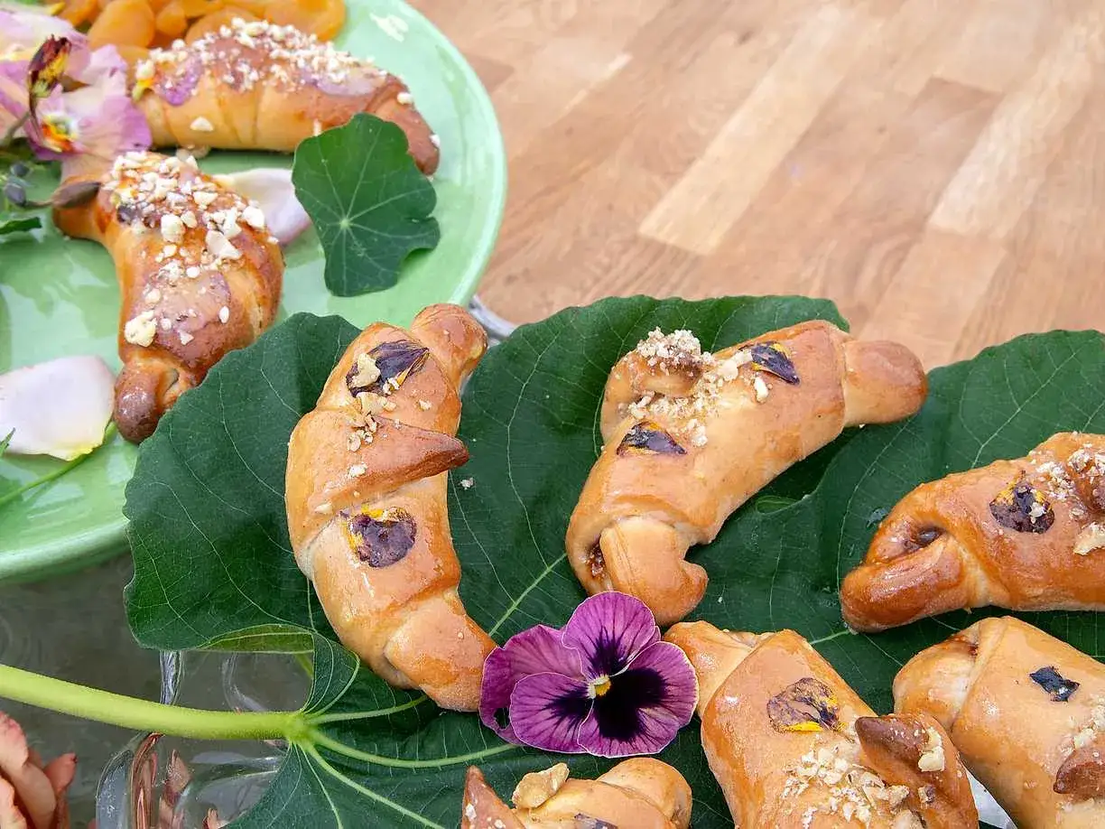 Gyllene gifflar med nötter och torkad frukt, vackert arrangerade på gröna blad. Ett härligt recept för fikastunden.